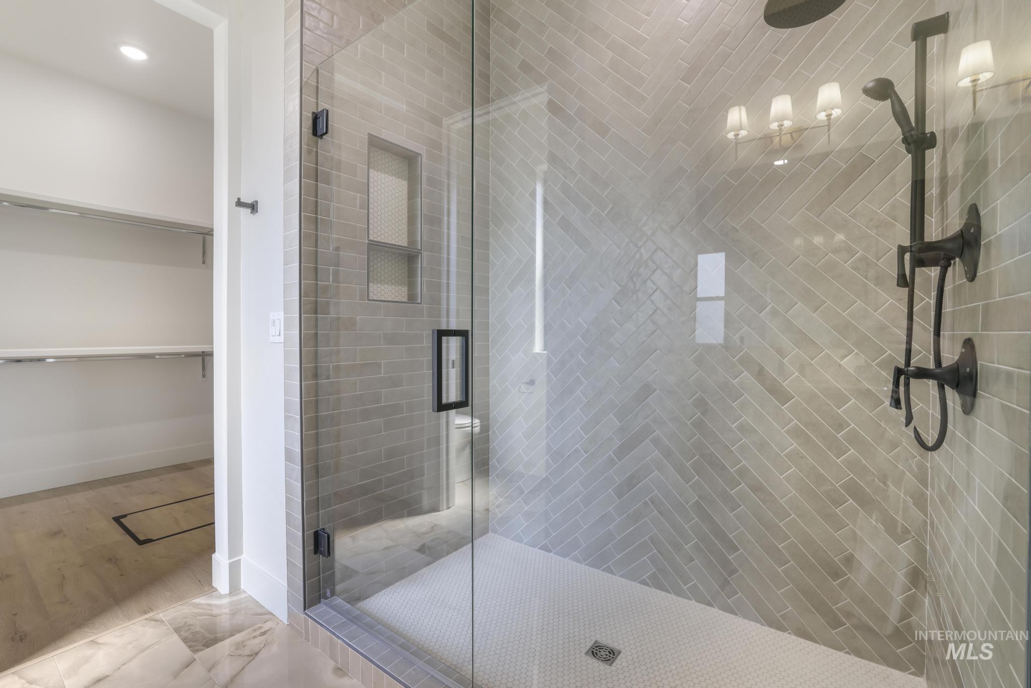 Full bathroom with a shower stall, a spacious closet, and marble finish flooring
