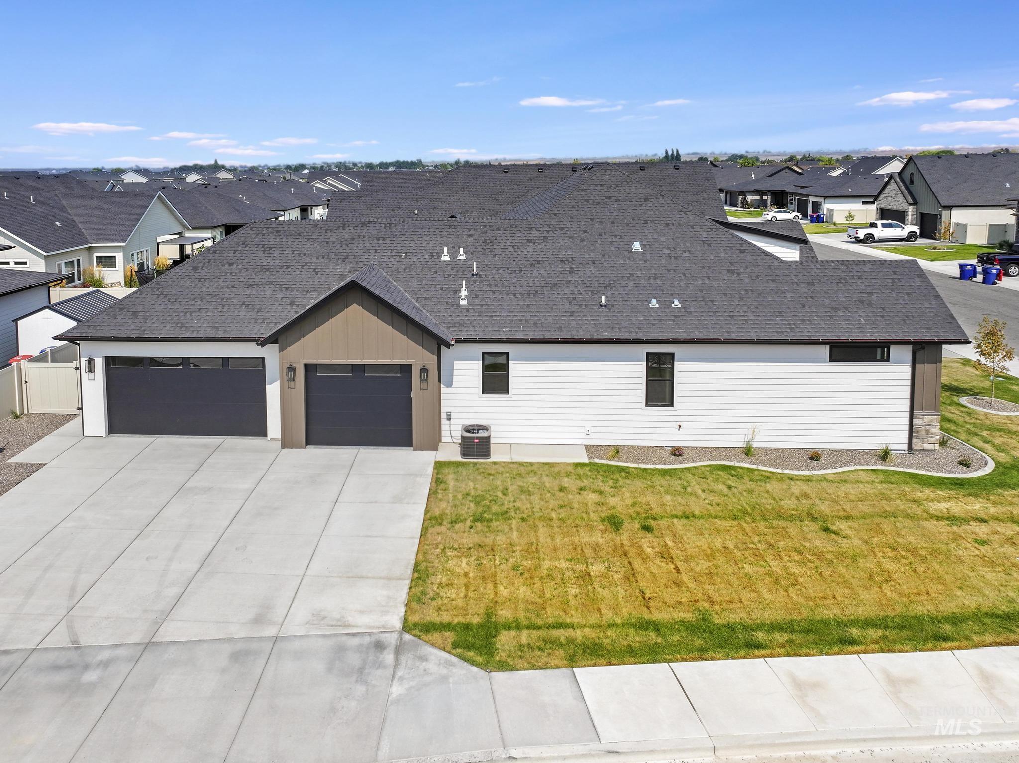 View of front facade with roof with shingles, a residential view, concrete driveway, an attached garage, and a front yard