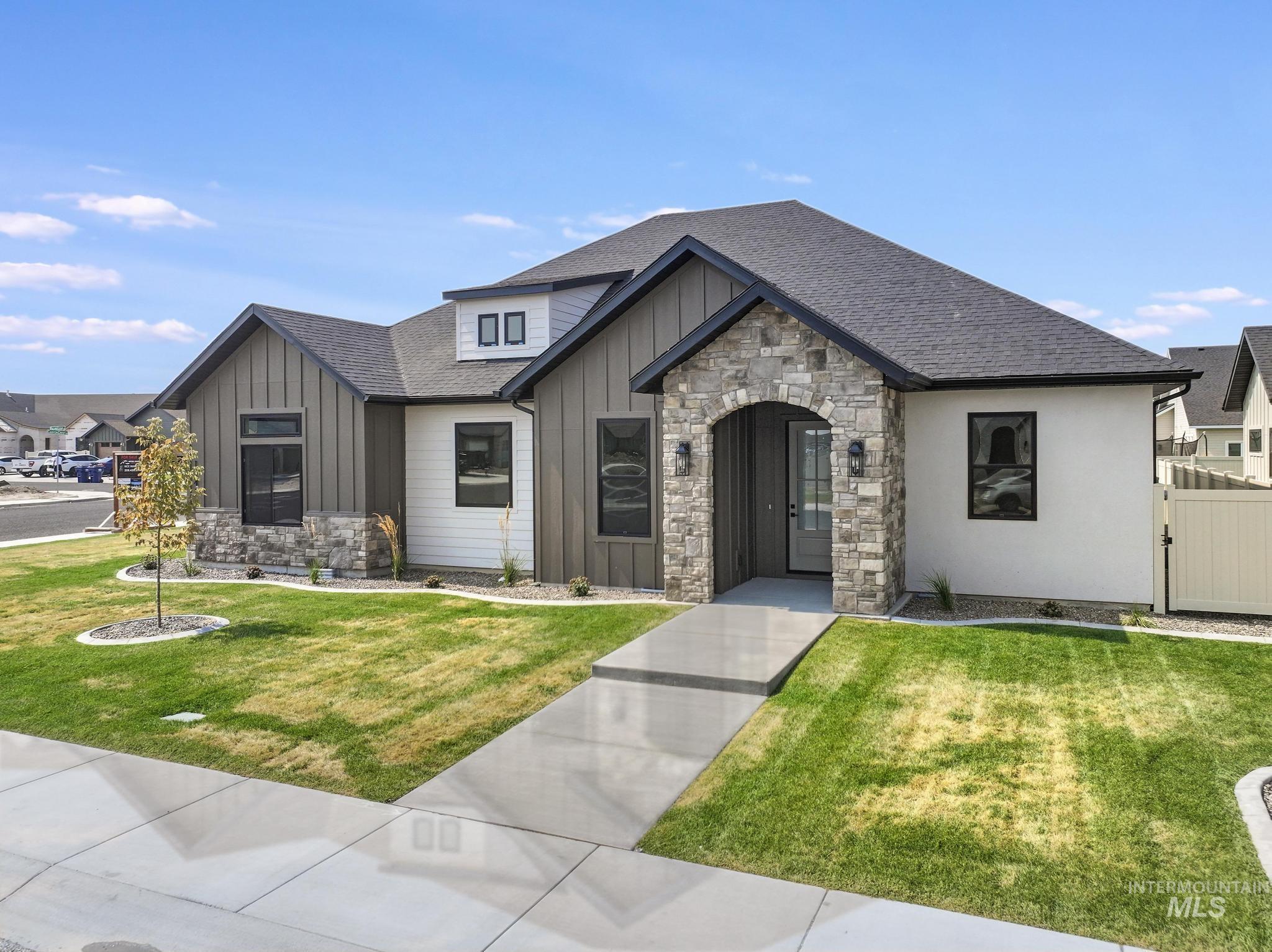 View of front of property with board and batten siding, stone siding, and roof with shingles