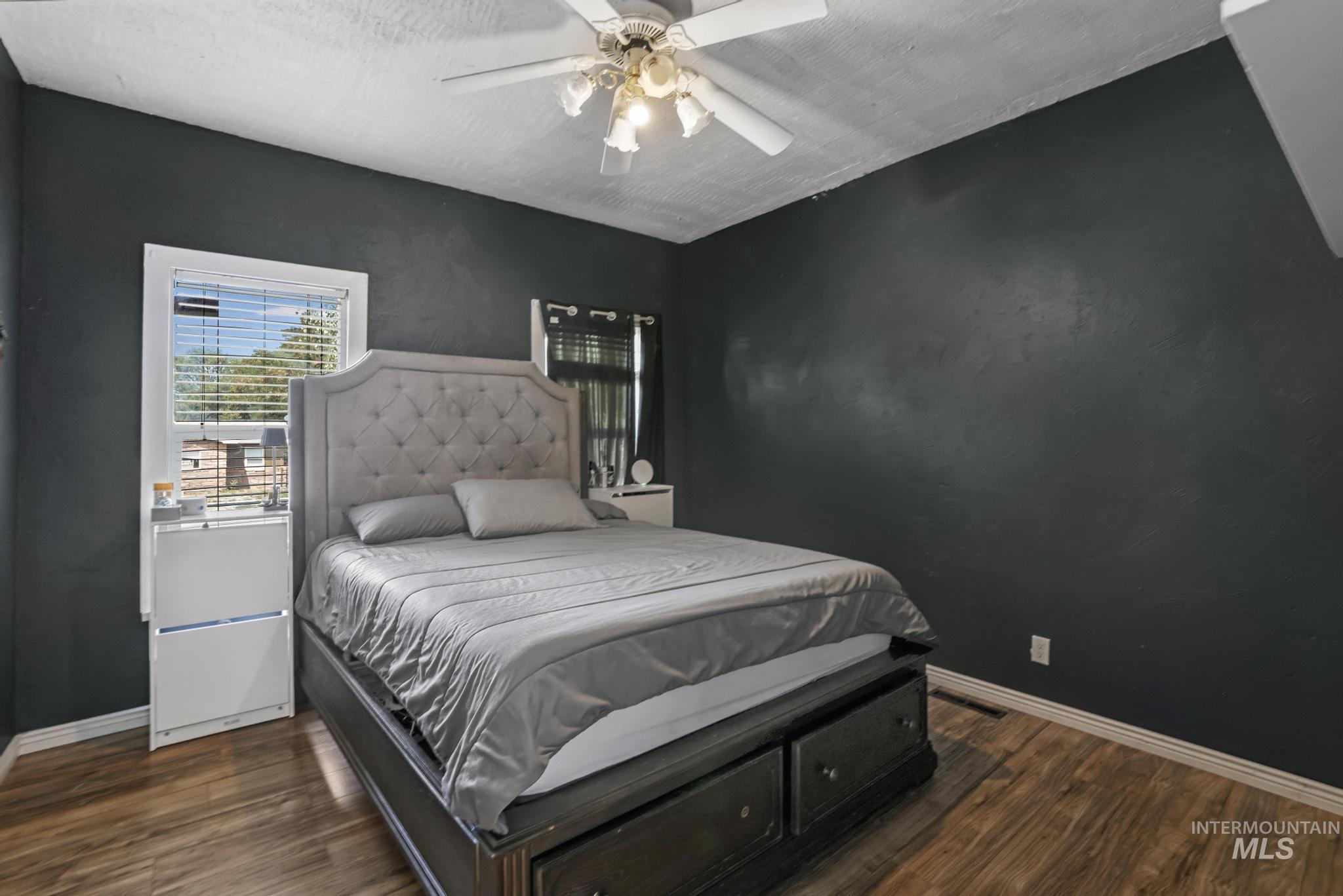 Bedroom featuring dark wood-style floors, a ceiling fan, and a textured ceiling