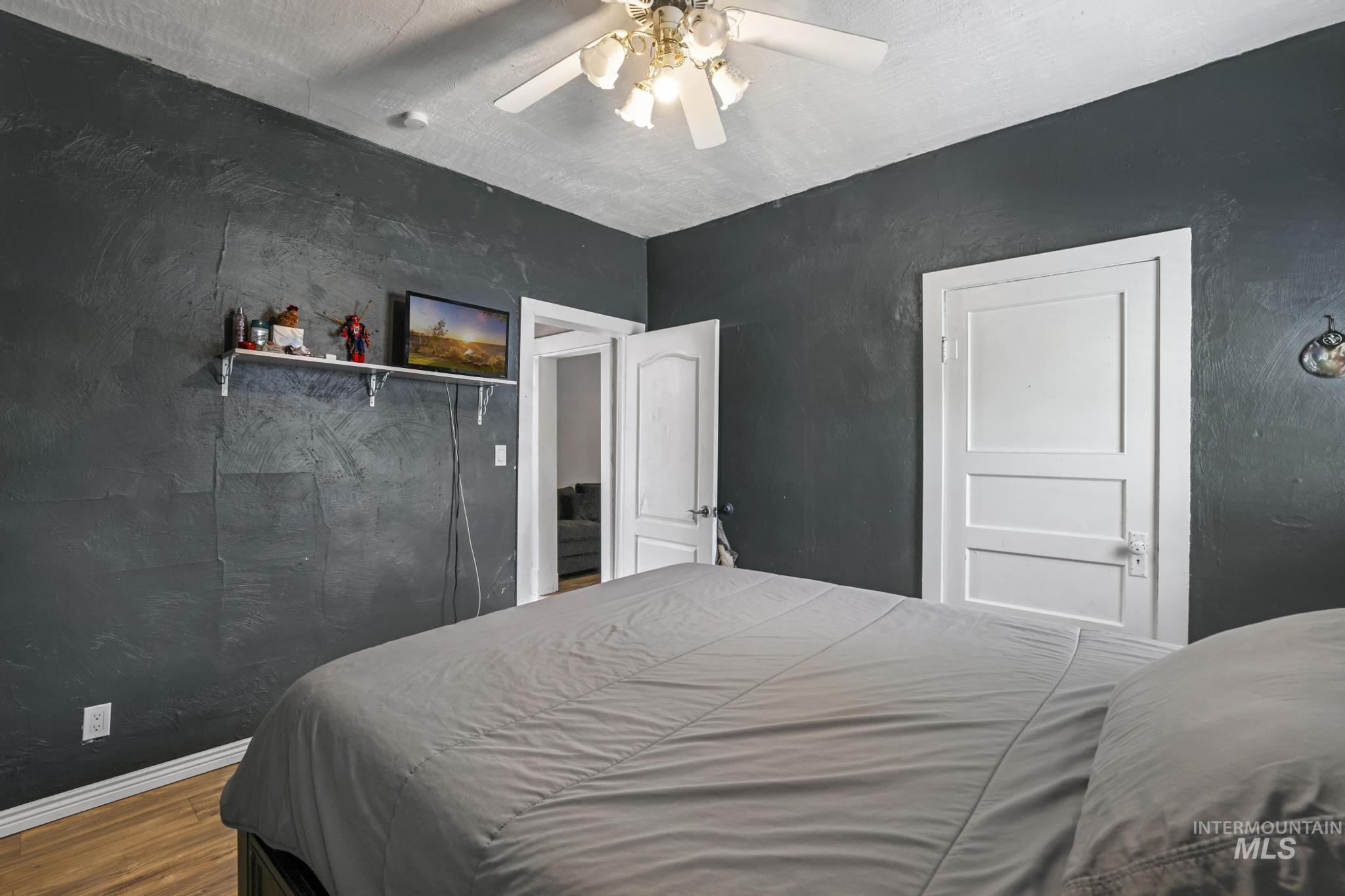 Bedroom featuring wood finished floors, ceiling fan, and a textured wall