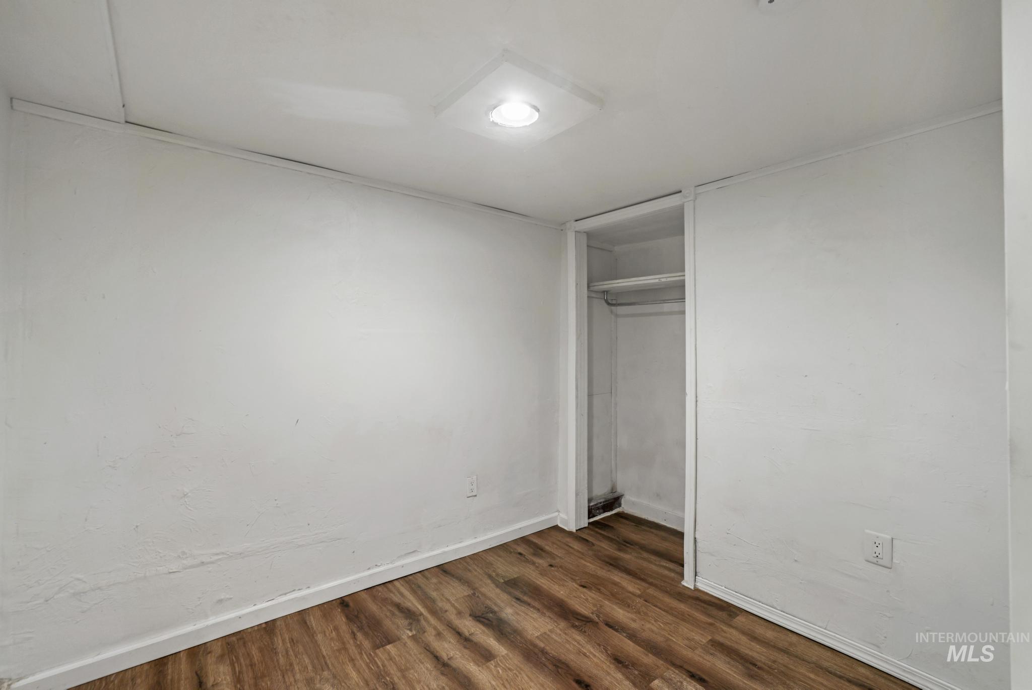 Unfurnished bedroom featuring dark wood-style floors and a closet