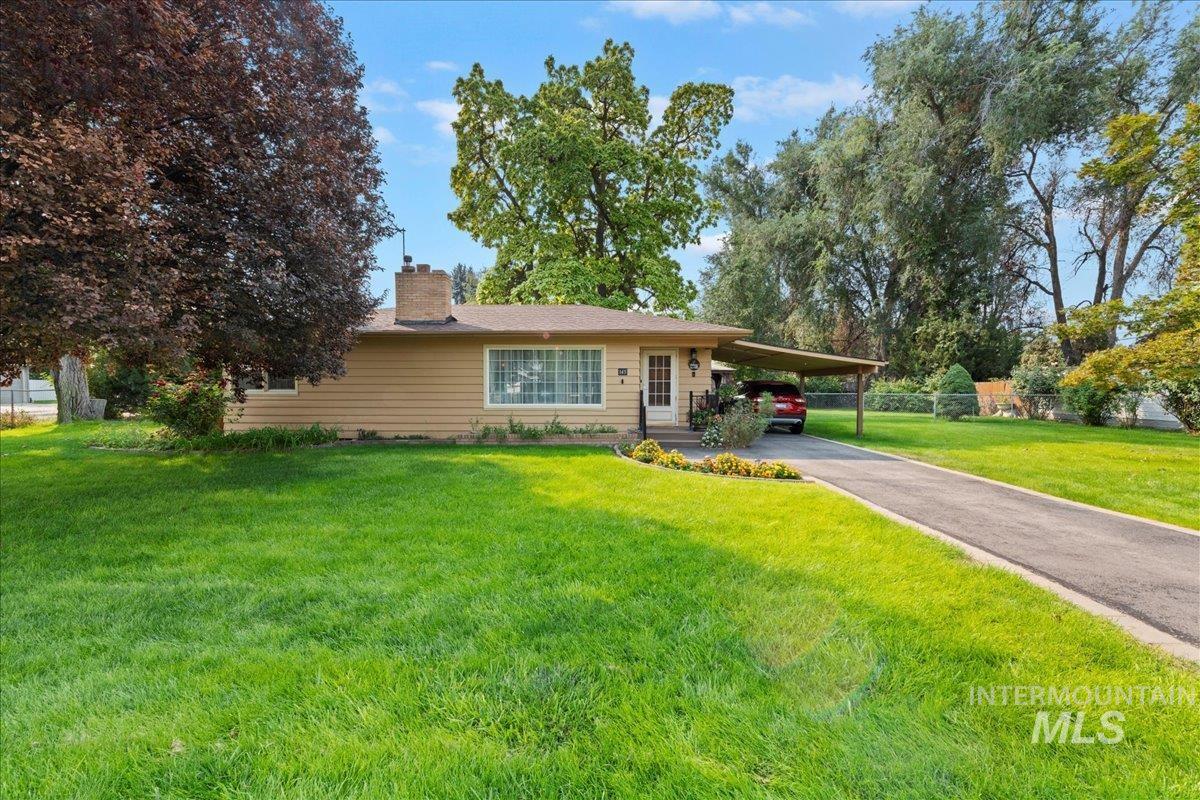 View of front of house with a chimney, asphalt driveway, a carport, and a front yard