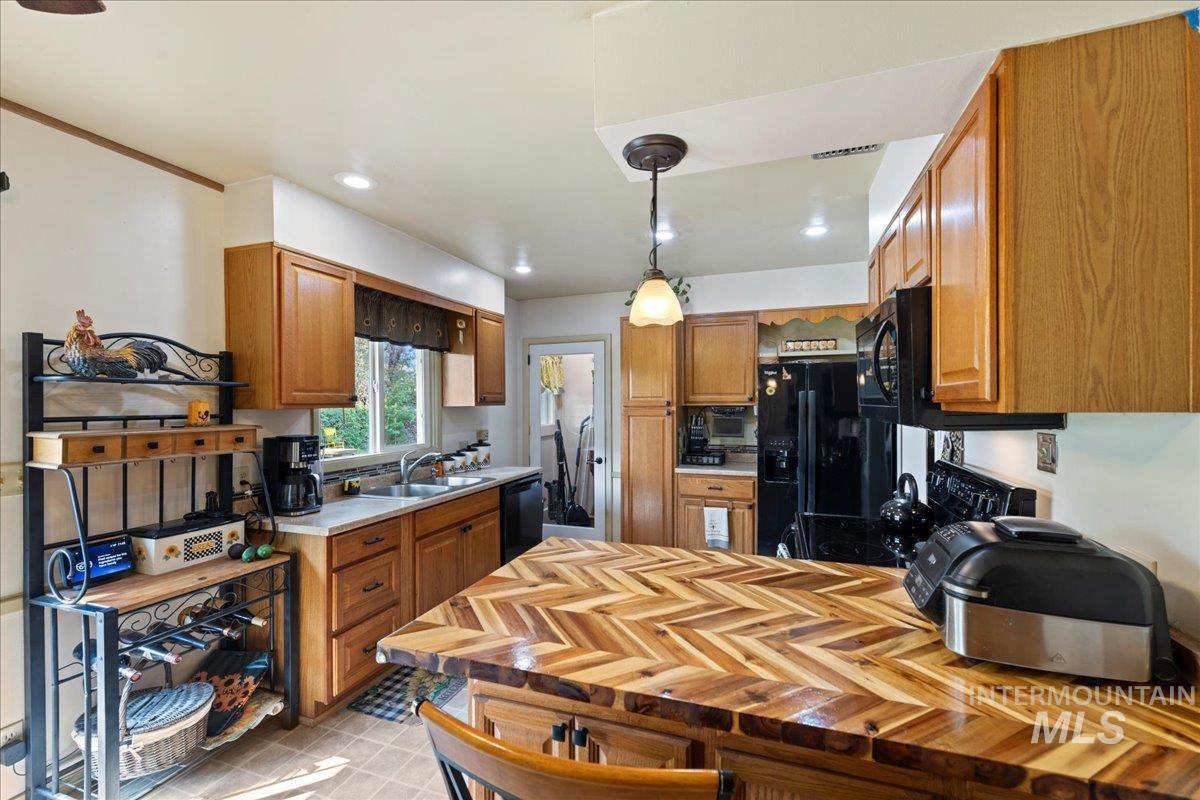 Kitchen featuring brown cabinets, black appliances, a peninsula, pendant lighting, and recessed lighting