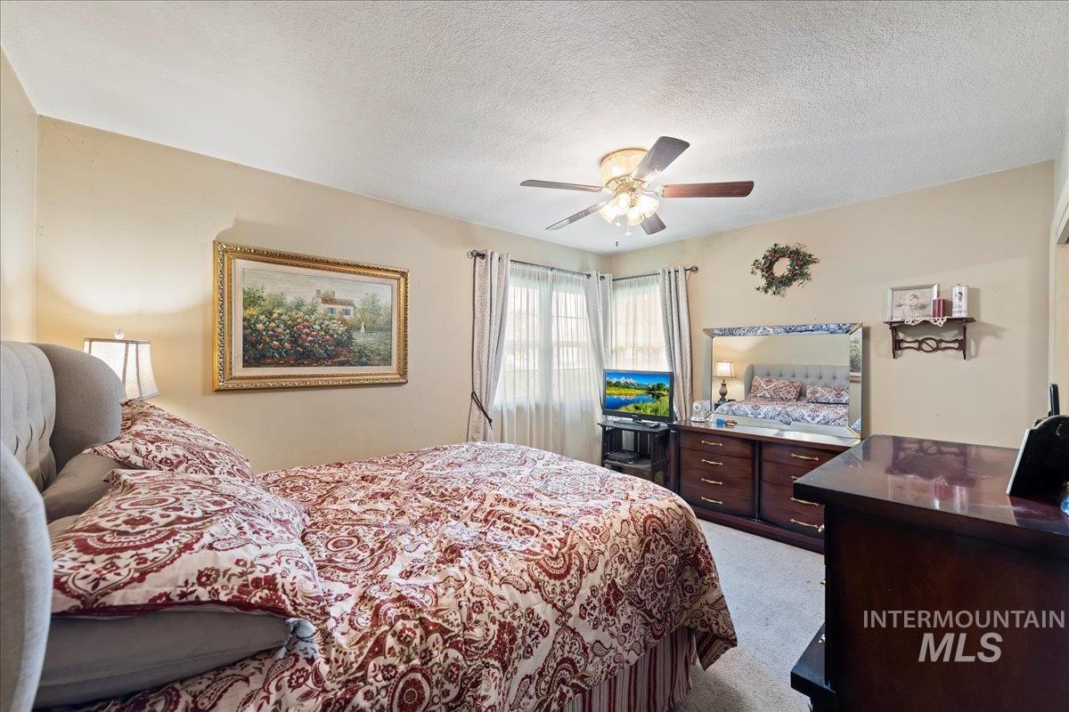 Bedroom featuring light carpet, a textured ceiling, and a ceiling fan