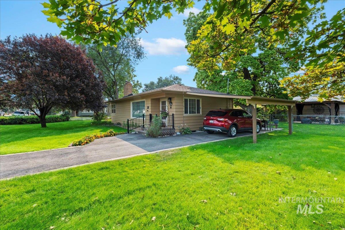 Ranch-style home with driveway, an attached carport, and a chimney