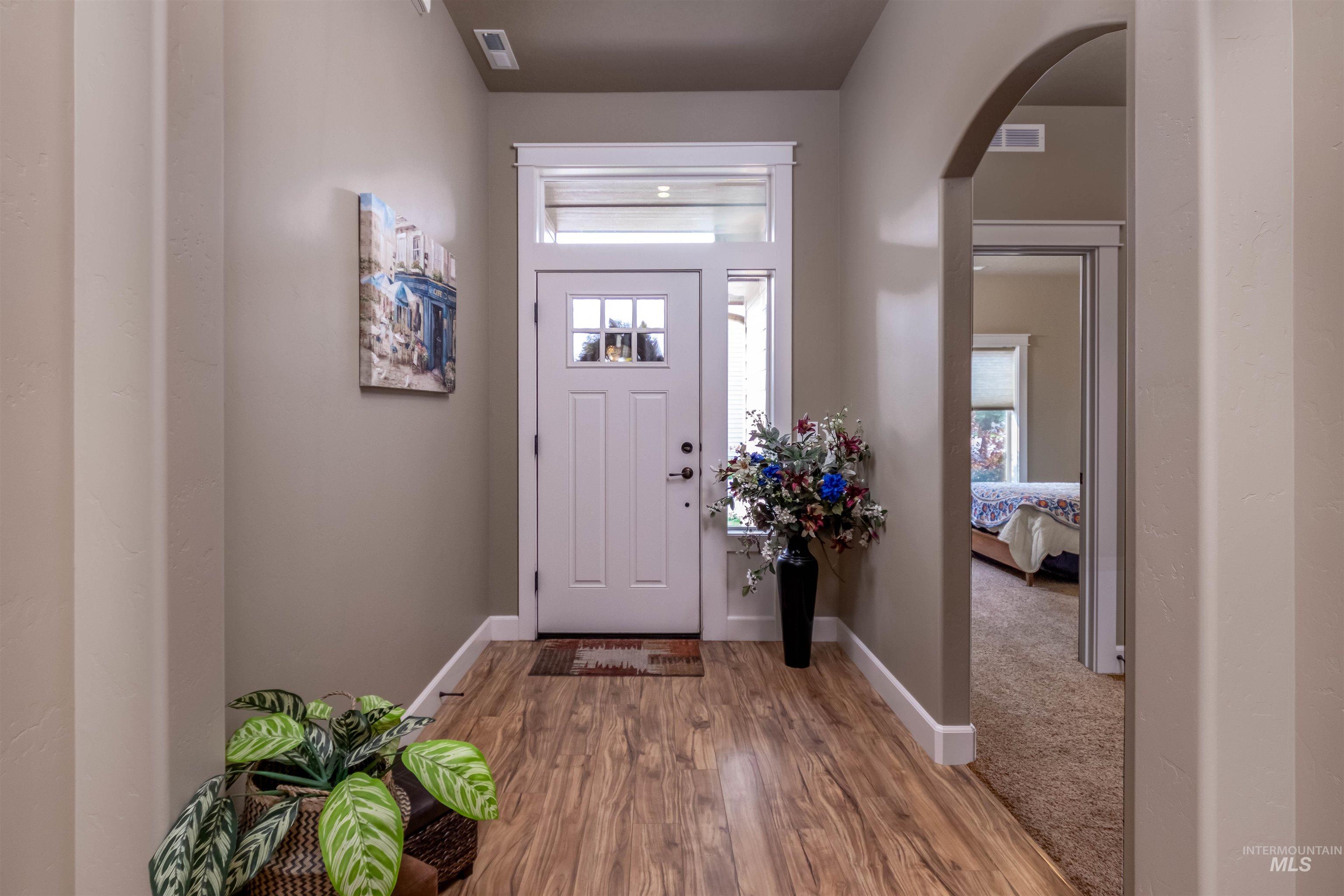 Entryway with plenty of natural light, wood finished floors, and arched walkways