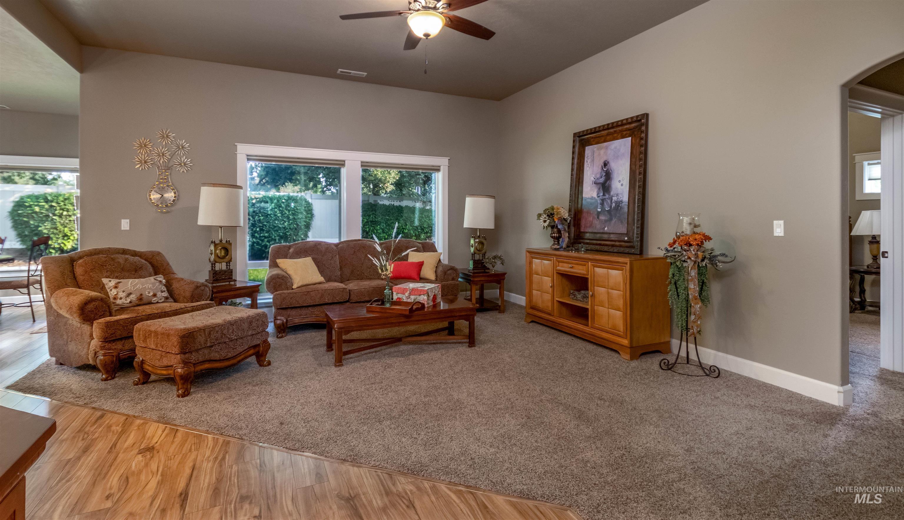 Living area featuring ceiling fan, arched walkways, and wood finished floors