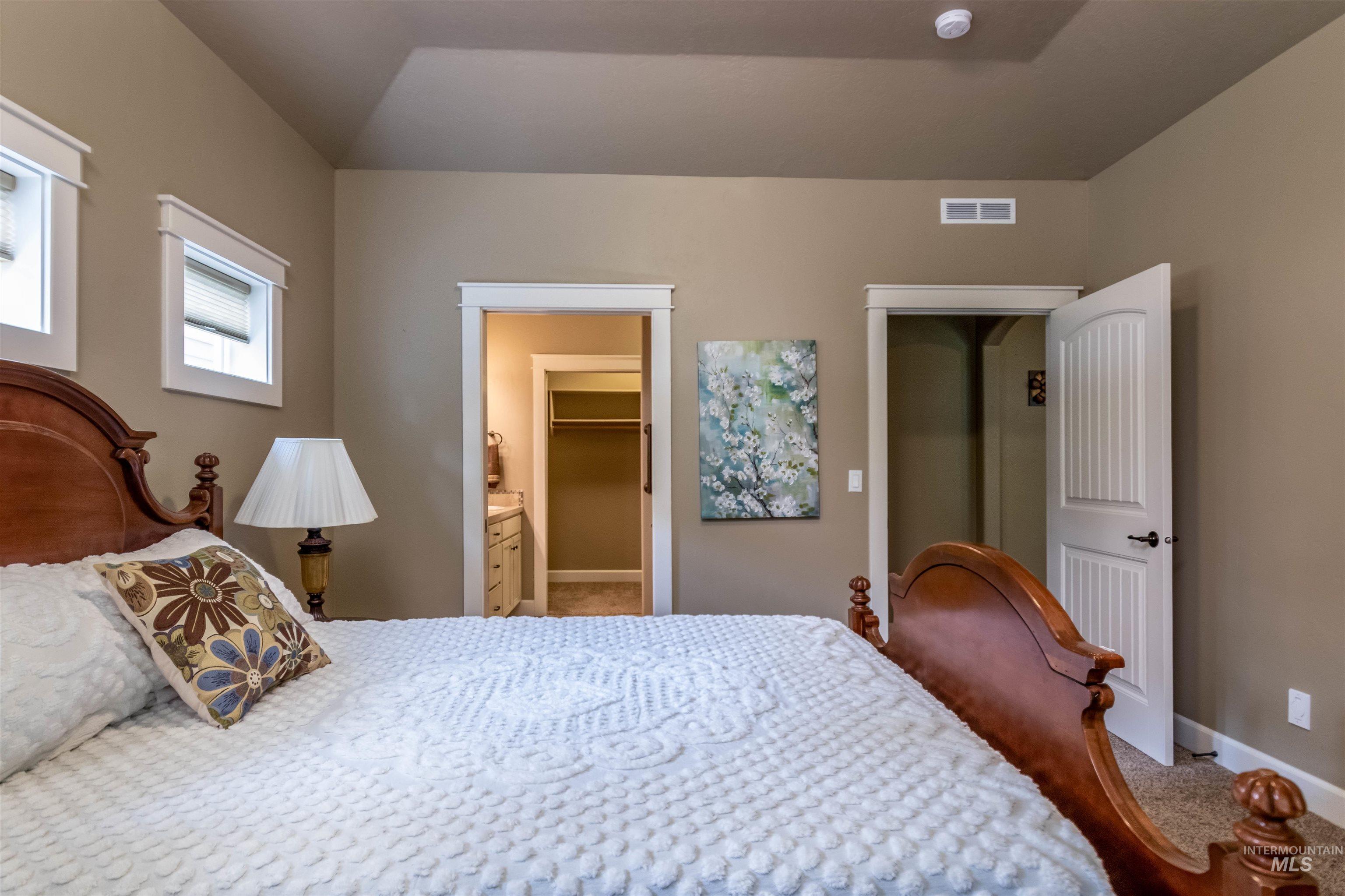 Carpeted bedroom featuring a walk in closet and ensuite bathroom