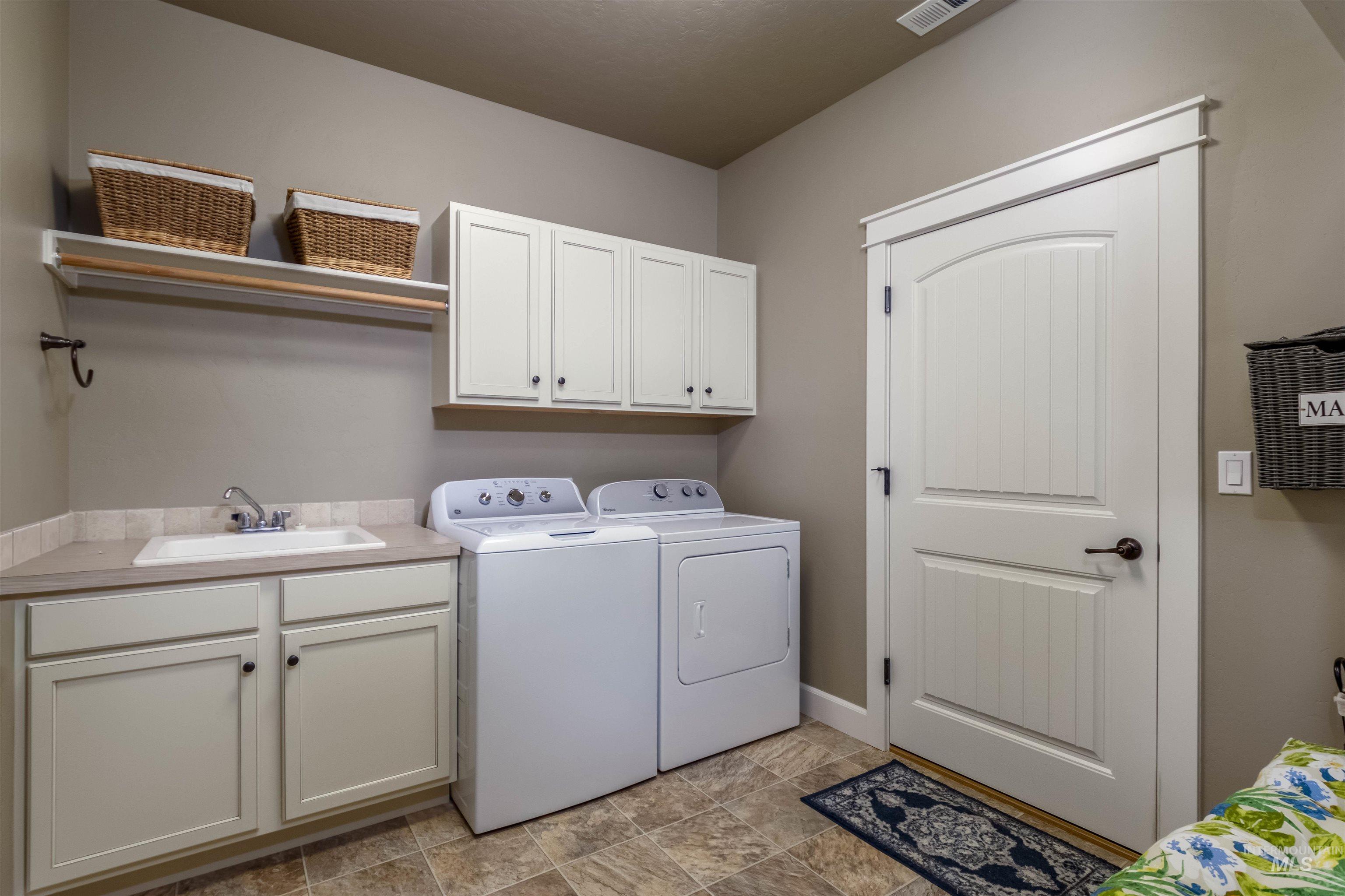 Laundry room featuring cabinet space, separate washer and dryer, and stone finish floors