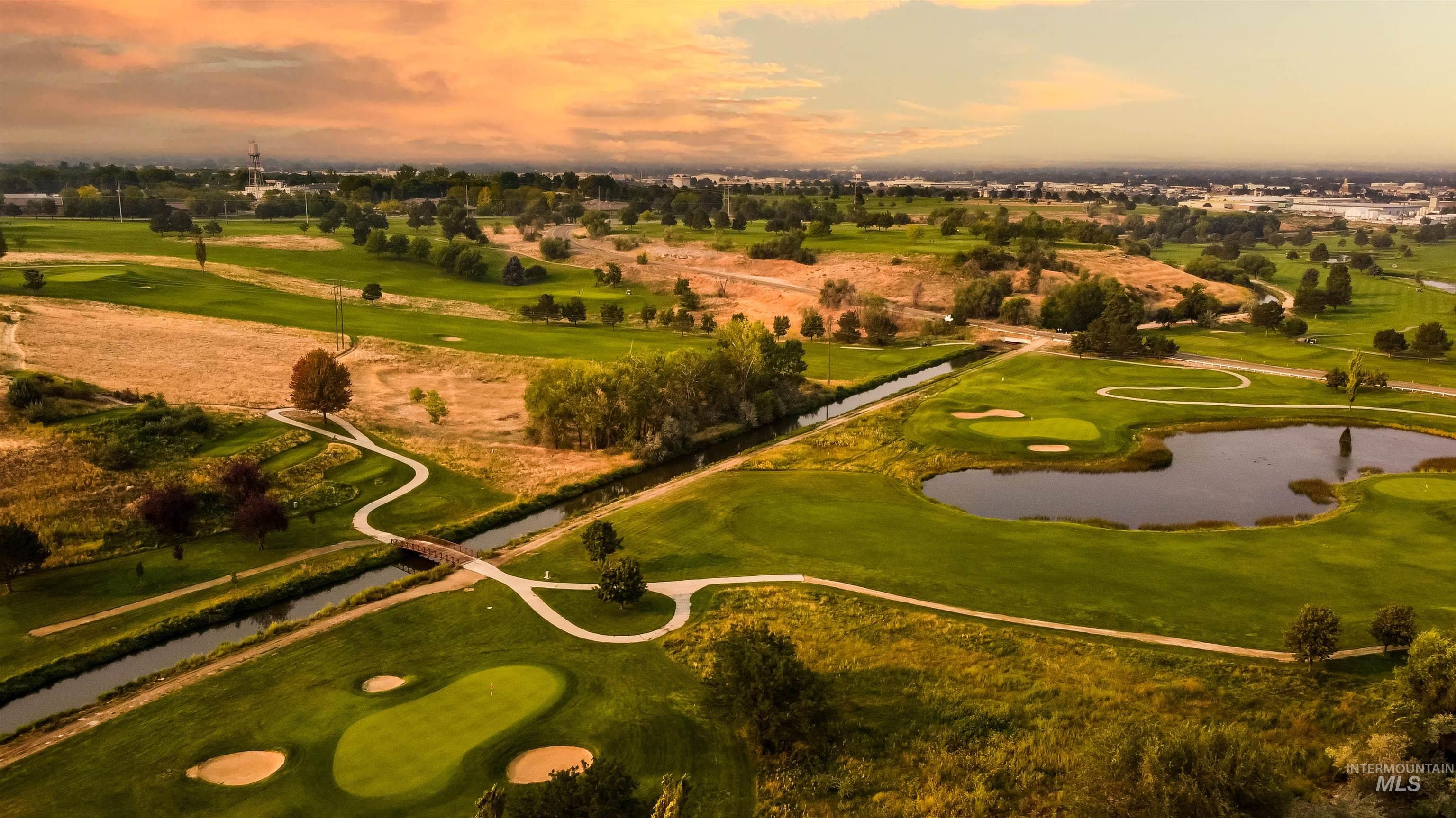Aerial view of property's location featuring a golf course and a nearby body of water