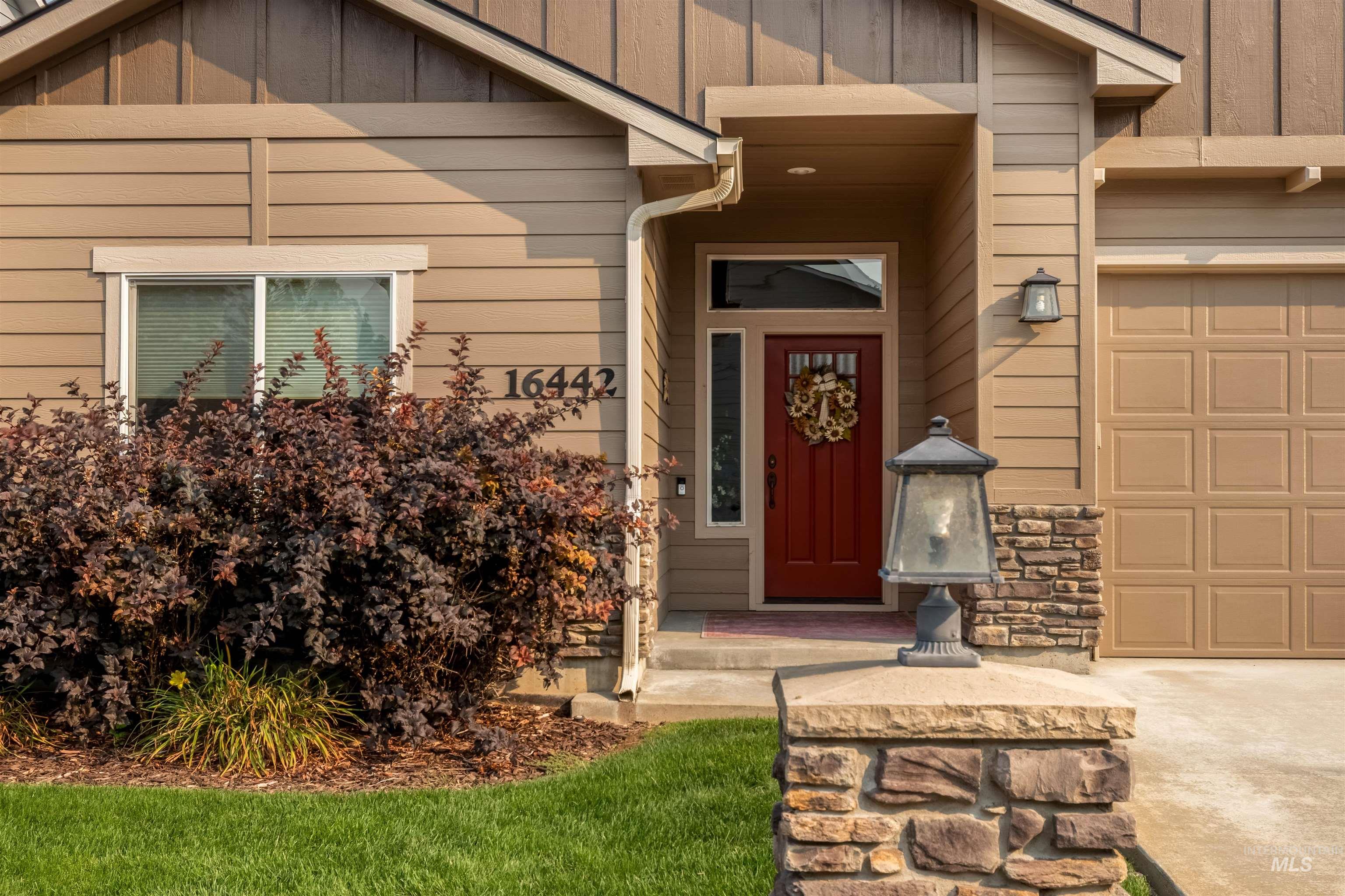 Property entrance with a garage, stone siding, and board and batten siding