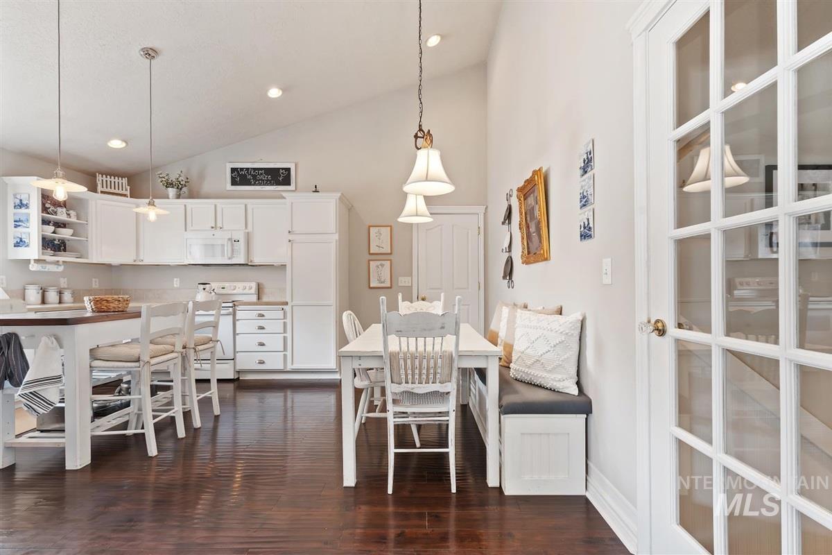 Dining room with dark wood-type flooring, high vaulted ceiling, and recessed lighting