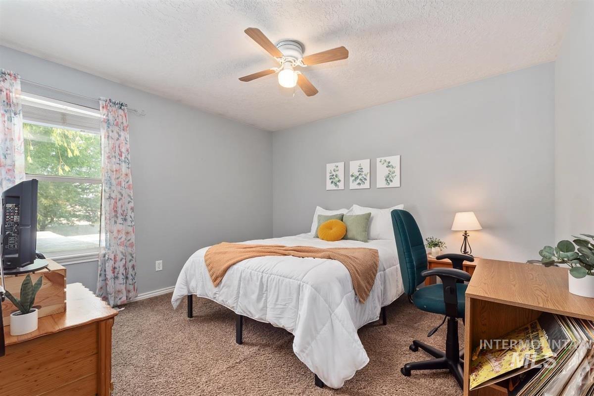 Carpeted bedroom with ceiling fan and a textured ceiling