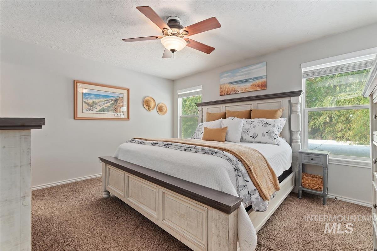 Bedroom with a textured ceiling, ceiling fan, and light carpet