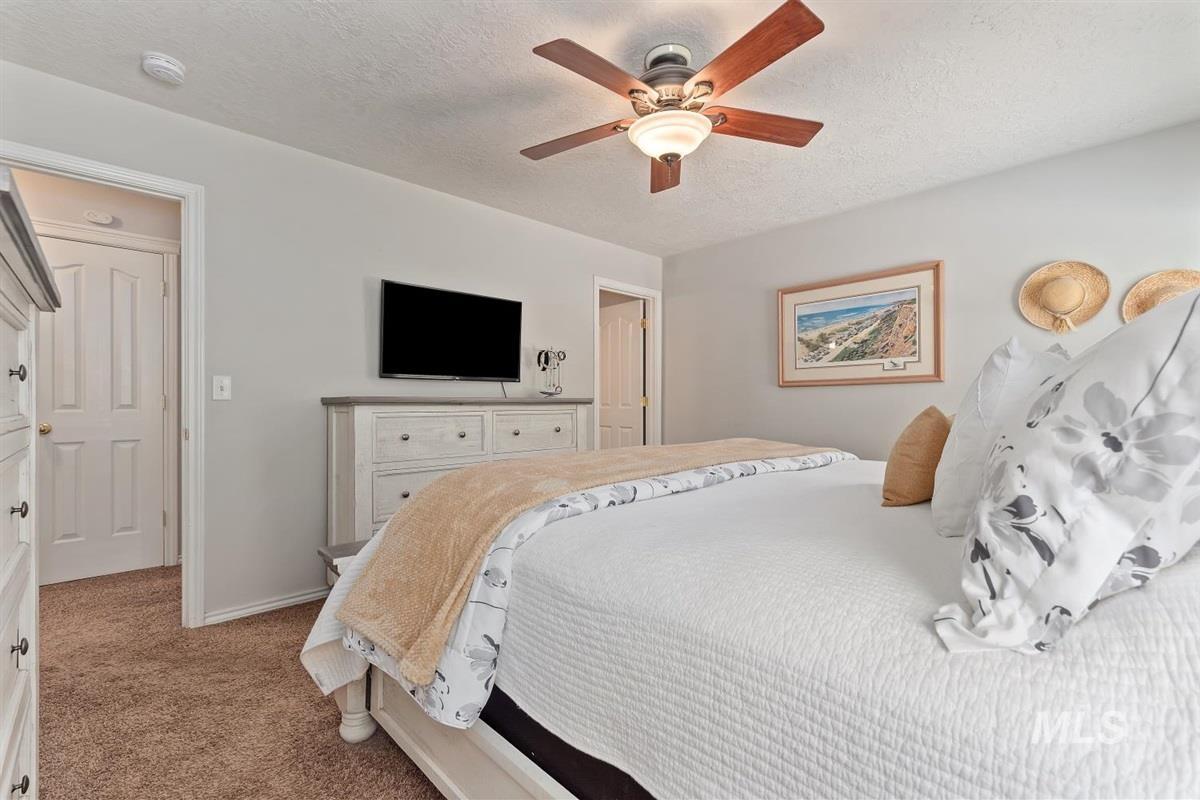 Bedroom with a textured ceiling, light colored carpet, and ceiling fan