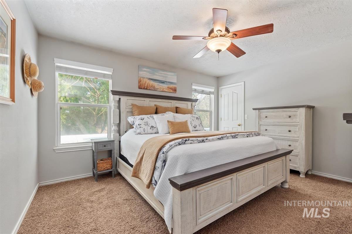 Bedroom featuring light carpet, a textured ceiling, and a ceiling fan