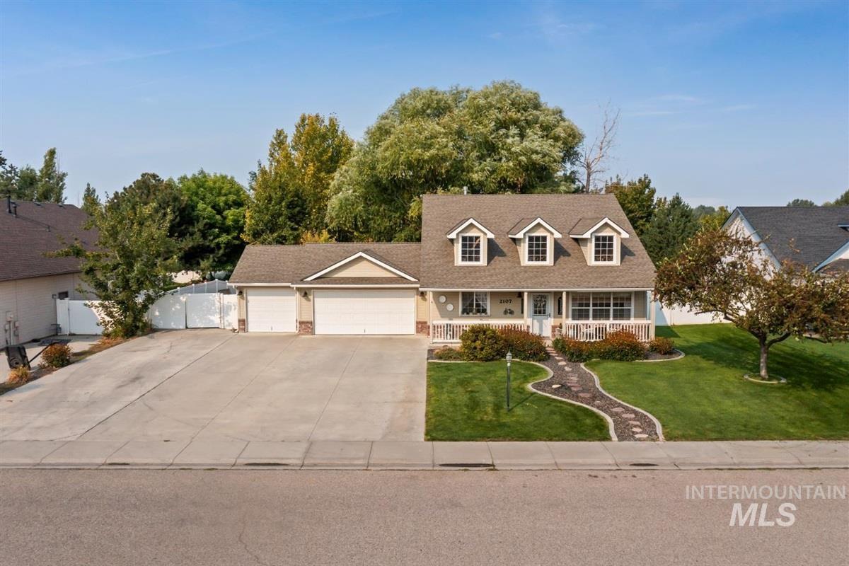 Cape cod home with covered porch, driveway, and an attached garage