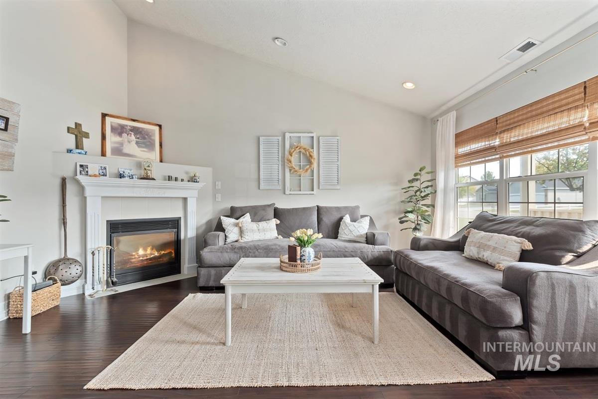 Living room with dark wood finished floors, a tile fireplace, high vaulted ceiling, and recessed lighting