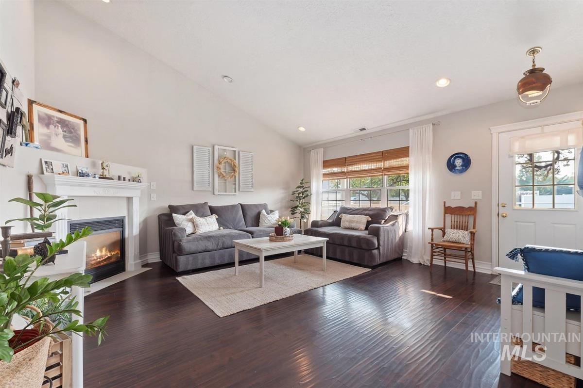 Living room with dark wood-style flooring, recessed lighting, a fireplace with flush hearth, and high vaulted ceiling
