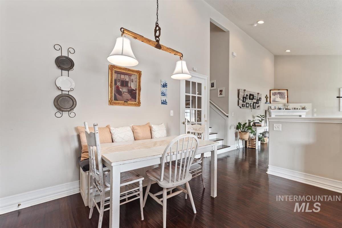 Dining room with dark wood-type flooring, a towering ceiling, stairs, and recessed lighting