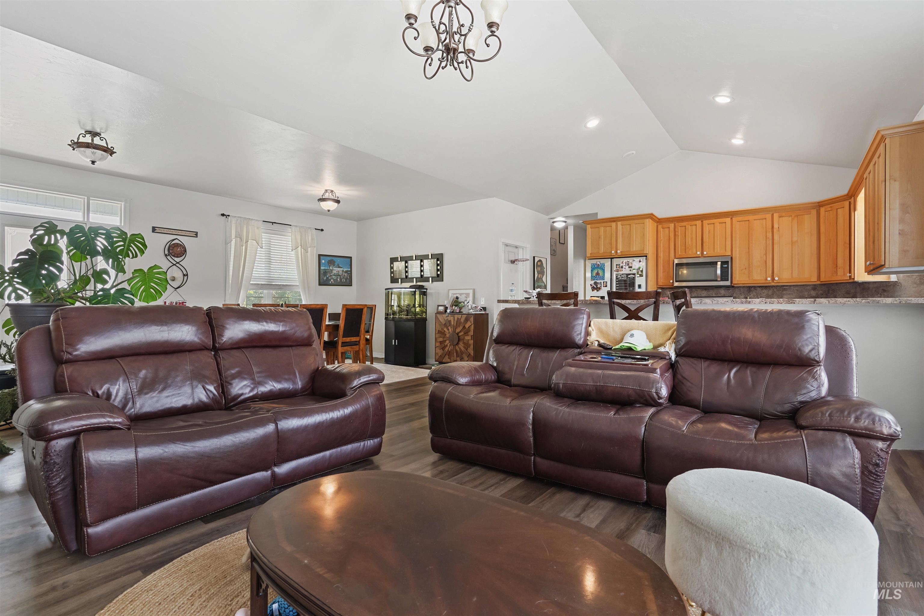 Living area with wood finished floors, a chandelier, and high vaulted ceiling