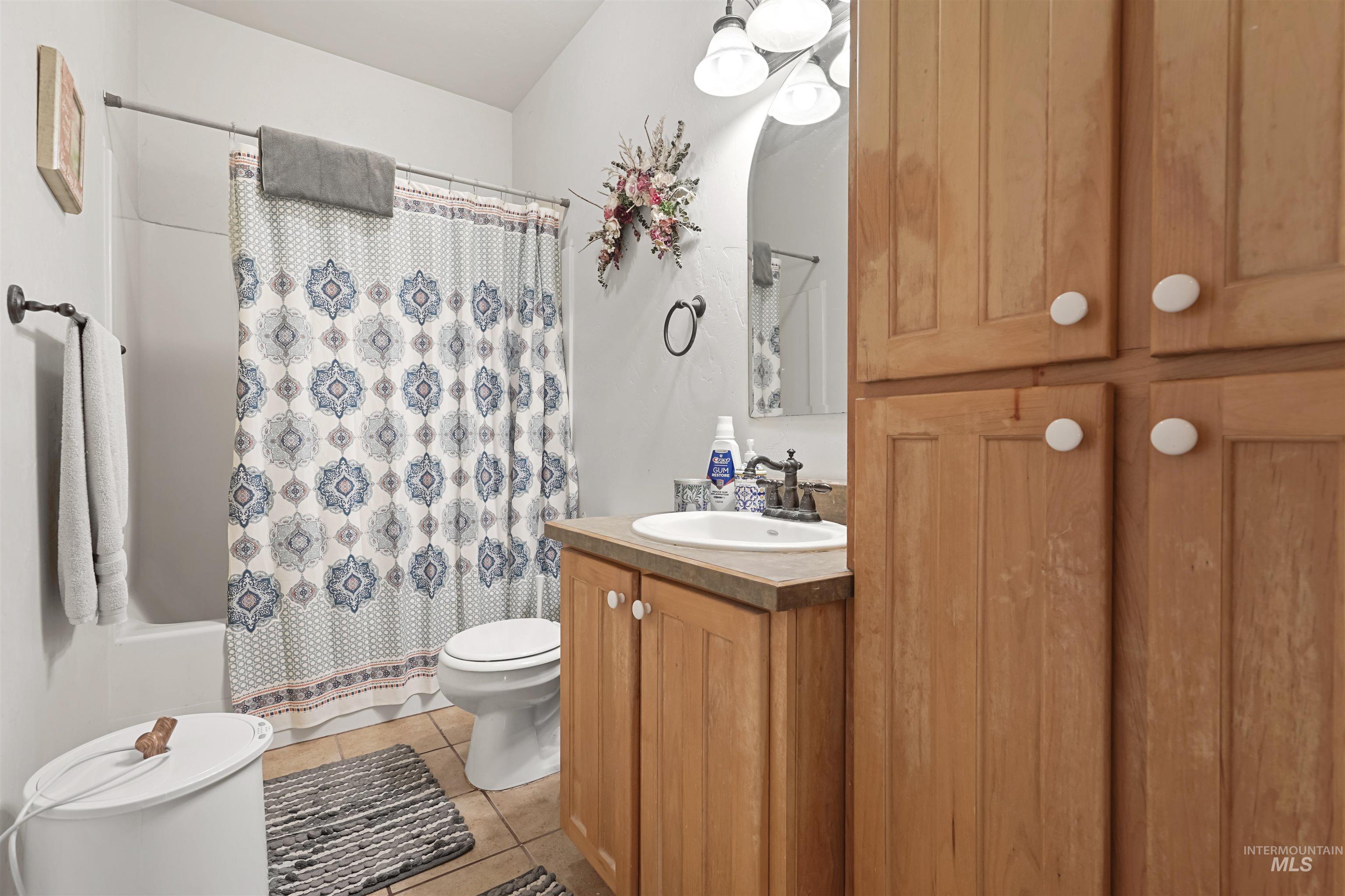 Bathroom featuring light tile patterned floors, vanity, and shower / bath combo with shower curtain