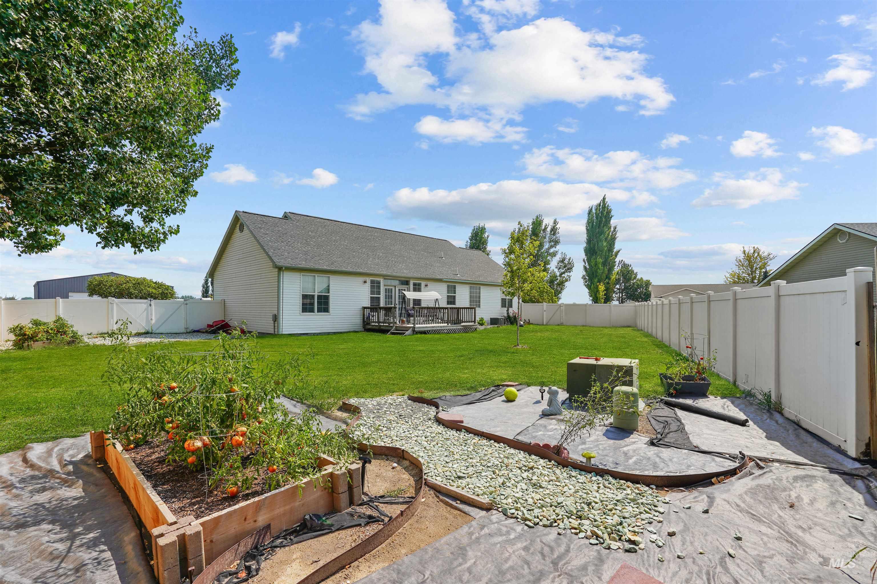 Fenced backyard featuring a wooden deck, a garden, and a patio area