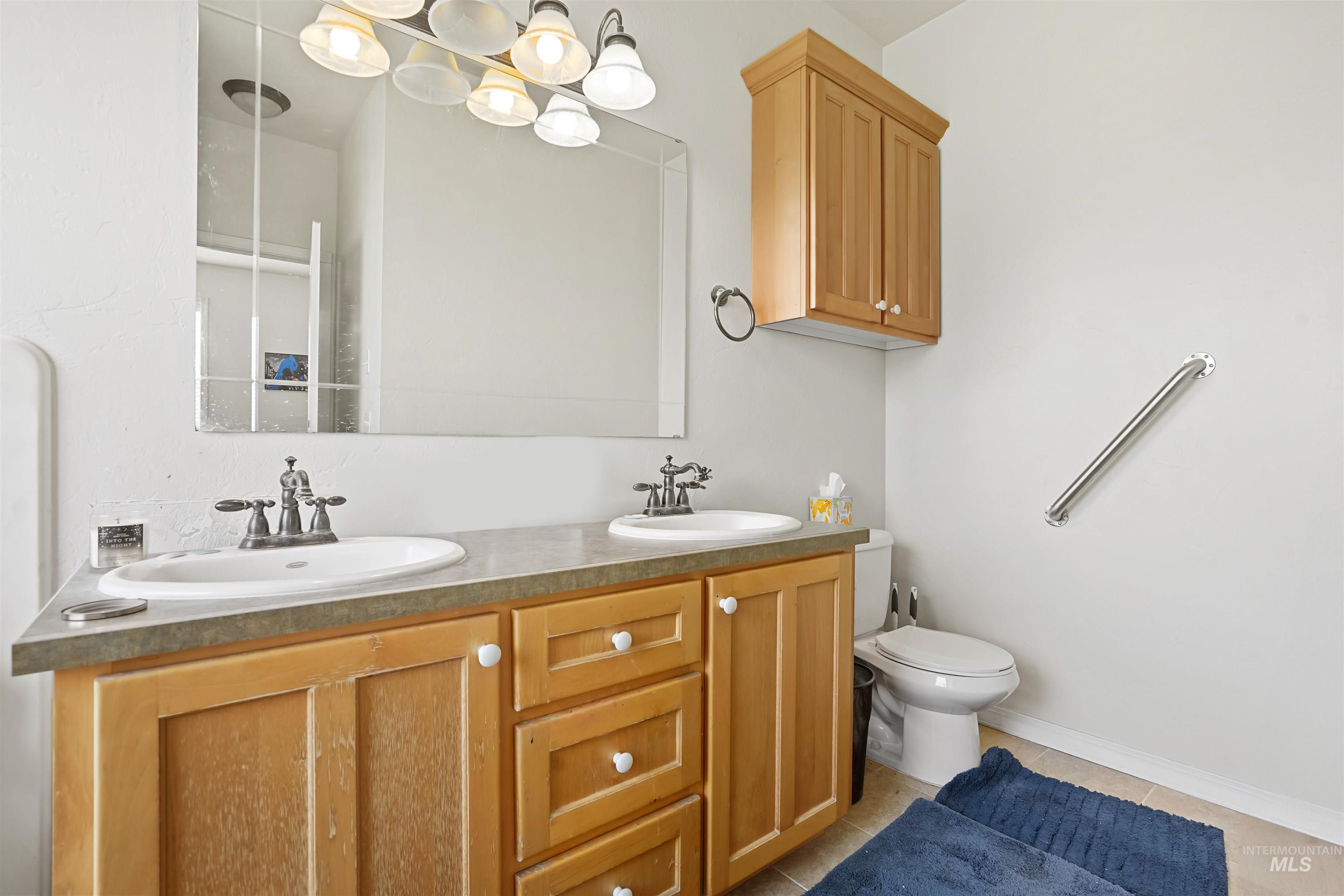 Bathroom with double vanity and light tile patterned floors