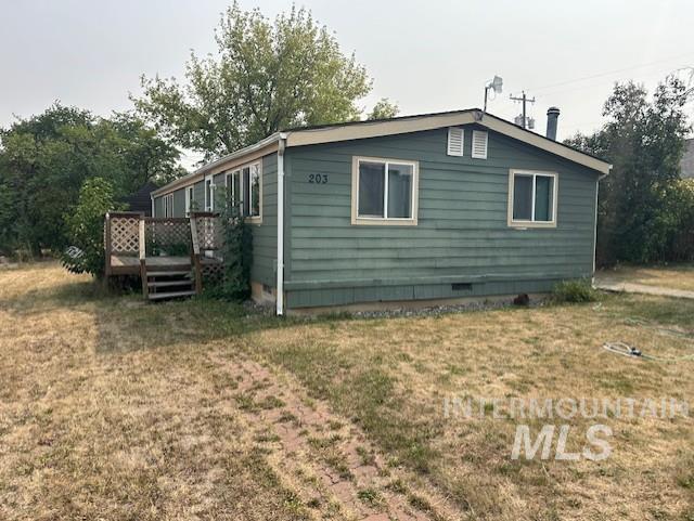 View of side of property featuring crawl space, a yard, and a deck