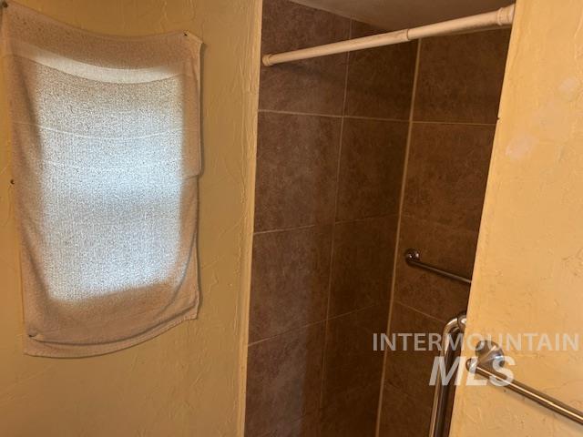 Full bathroom with a textured wall and a shower stall