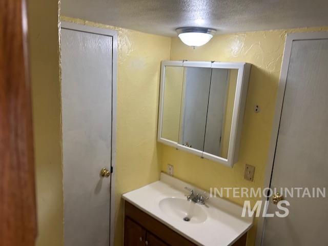 Bathroom with vanity, a textured ceiling, and a textured wall