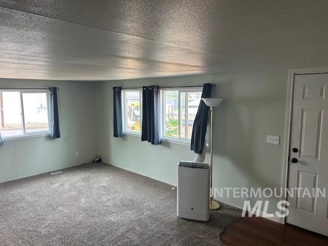 Spare room featuring a textured ceiling and dark carpet