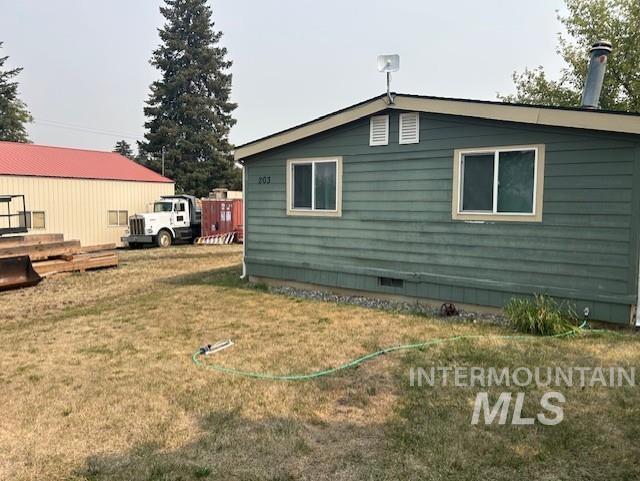 View of side of property featuring a yard and crawl space