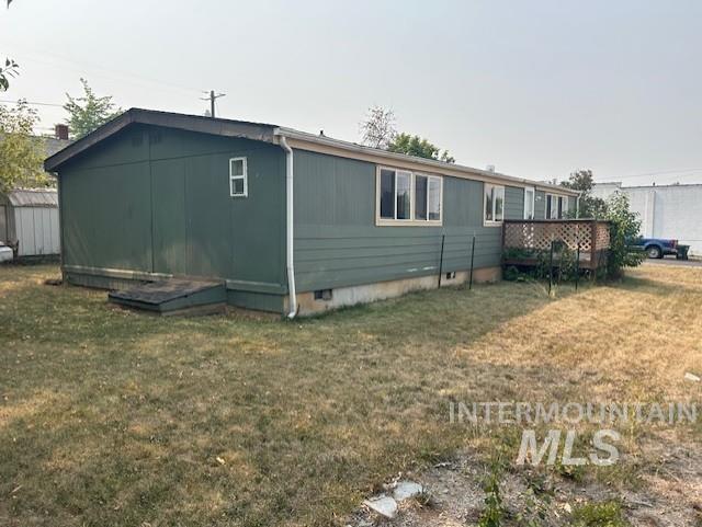 View of property exterior featuring crawl space, a lawn, and a wooden deck