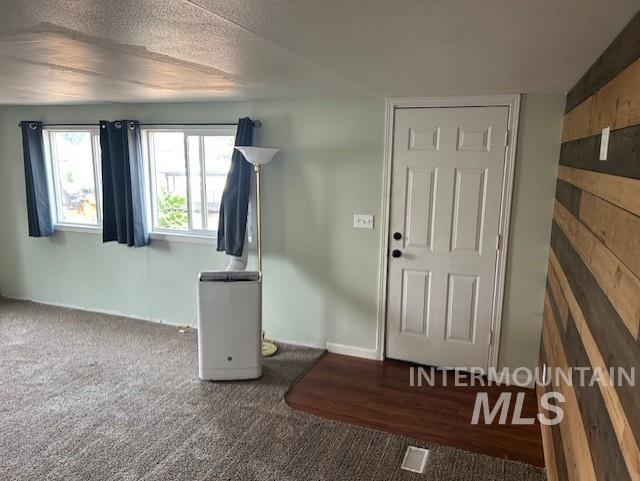 Foyer entrance with dark carpet and a textured ceiling