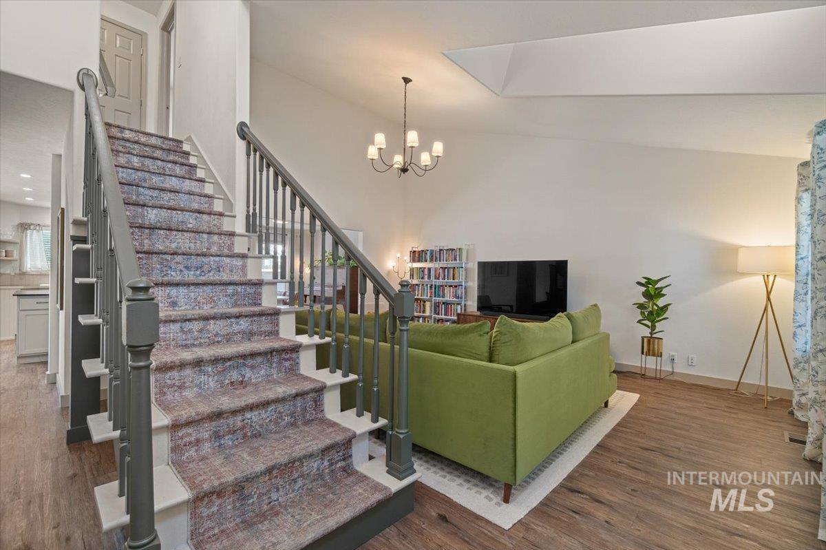 Living room with dark wood-type flooring, stairway, and a chandelier
