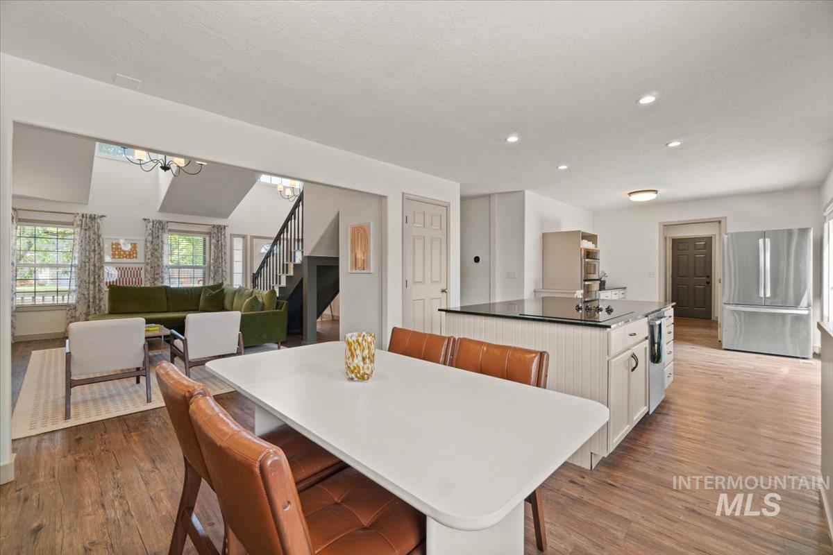 Dining area with stairway, light wood-style flooring, a chandelier, recessed lighting, and a textured ceiling