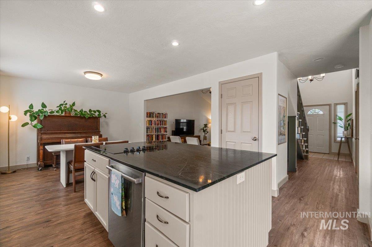 Kitchen with white cabinetry, a center island, dark wood-style flooring, a textured ceiling, and dark stone counters