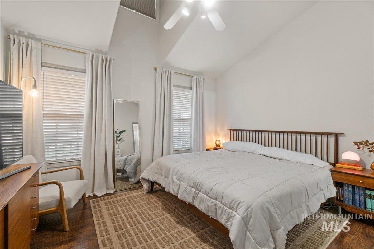 Bedroom featuring dark wood-style flooring, high vaulted ceiling, and a ceiling fan