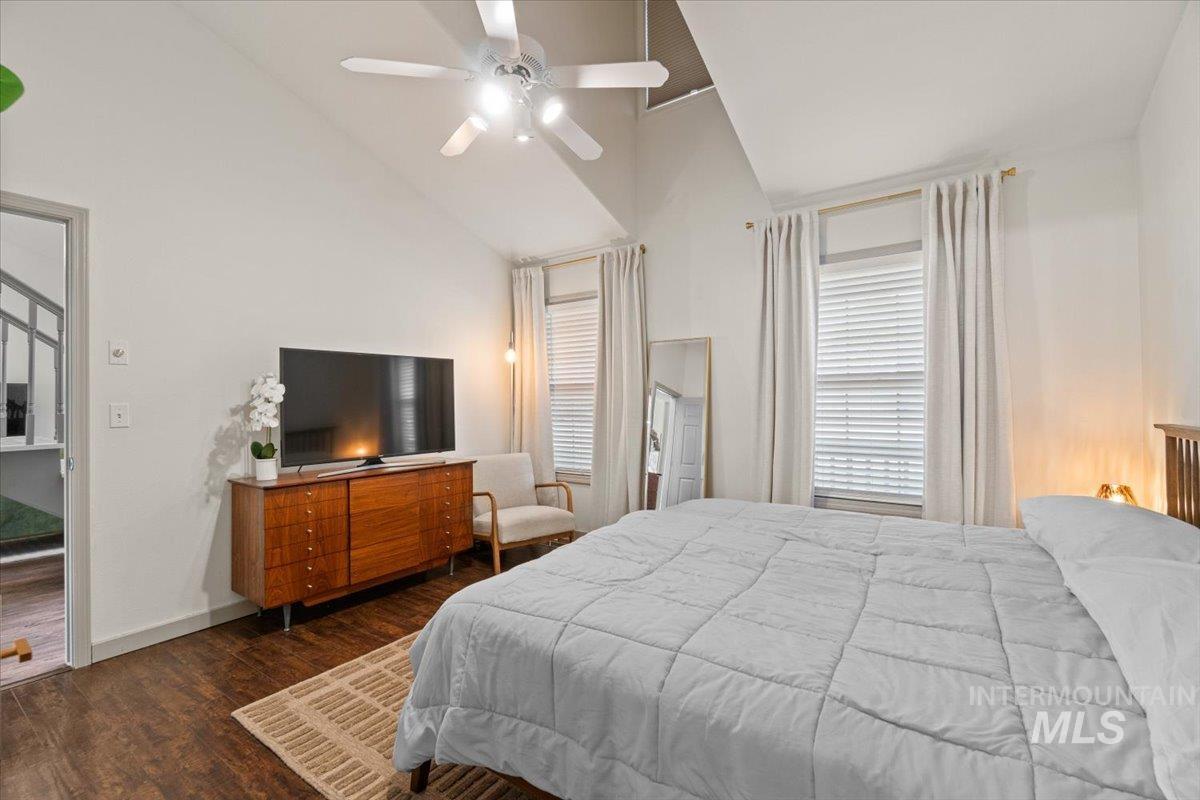 Bedroom with dark wood-type flooring, high vaulted ceiling, and a ceiling fan