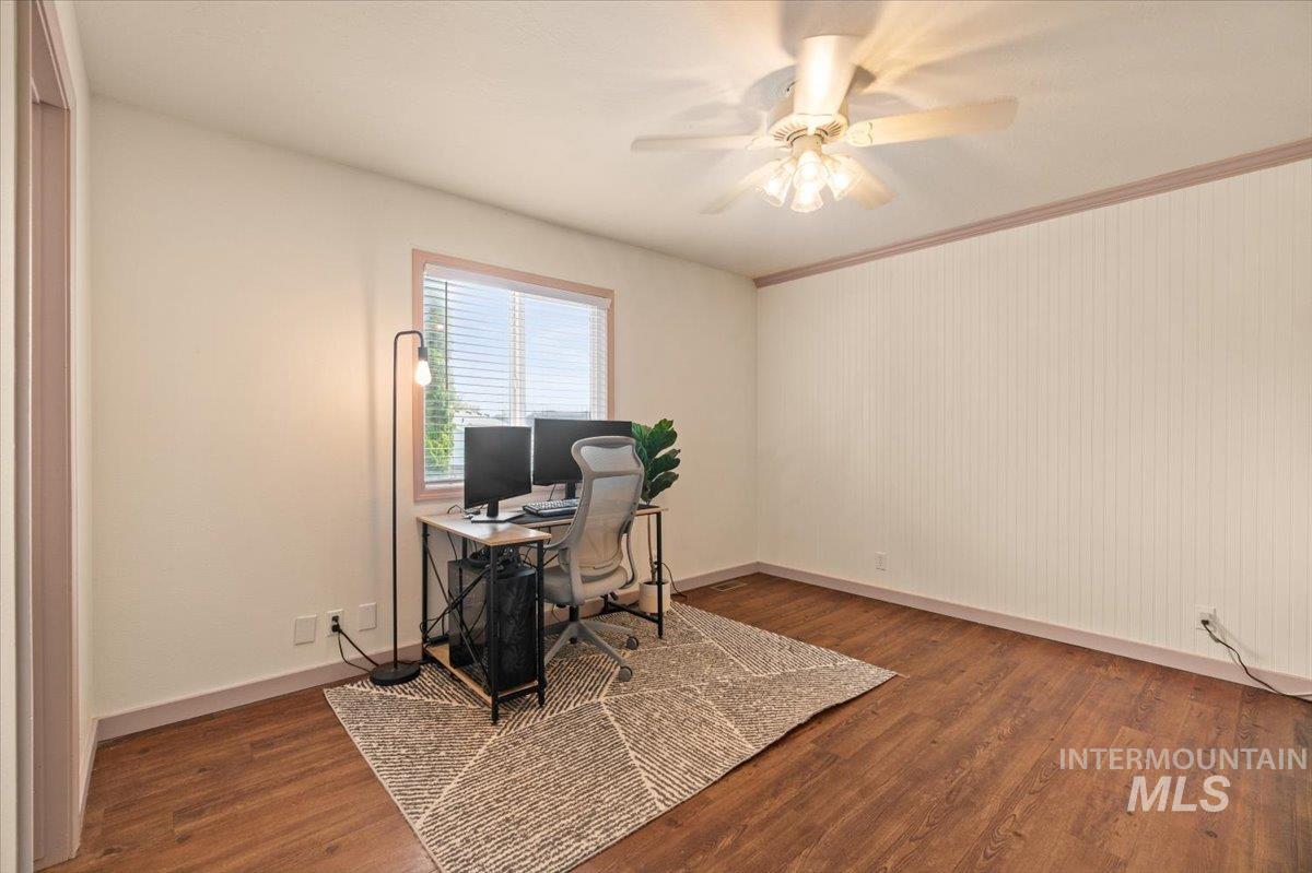Office with dark wood-style flooring, ceiling fan, and crown molding