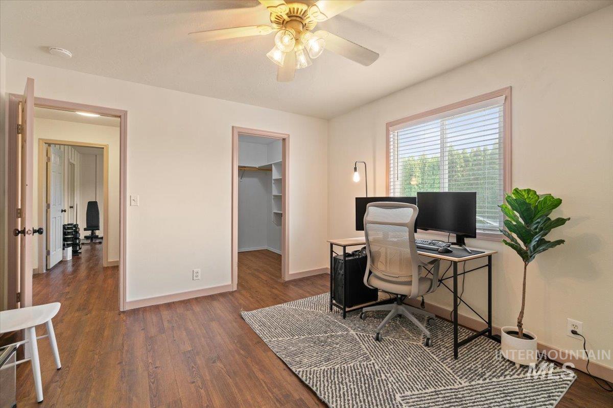 Office area with dark wood-style flooring and a ceiling fan