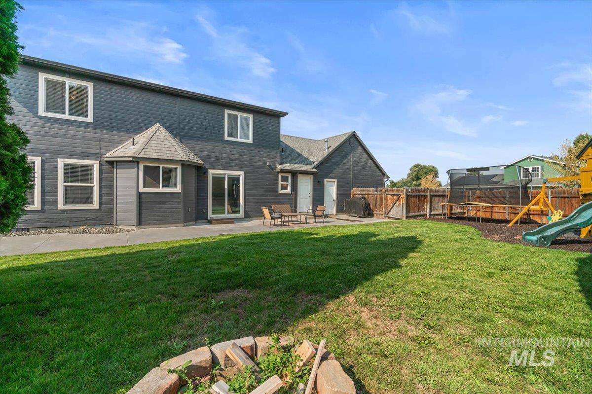 Back of house featuring a playground, a trampoline, a patio, and roof with shingles