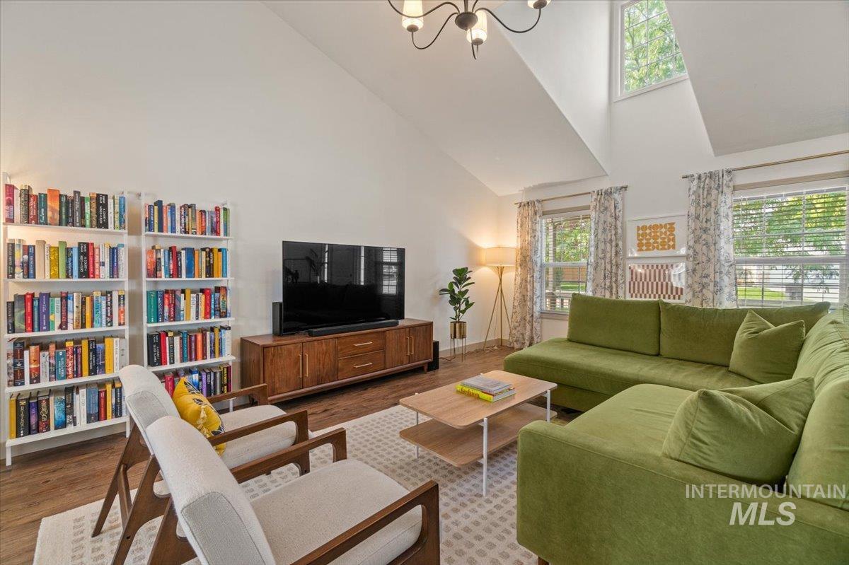 Living area featuring high vaulted ceiling, light wood finished floors, and a chandelier