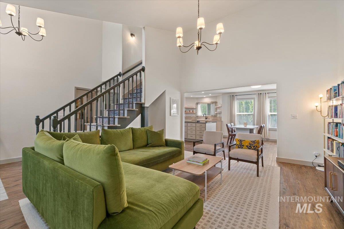 Living area featuring a chandelier, wood finished floors, a high ceiling, and stairway