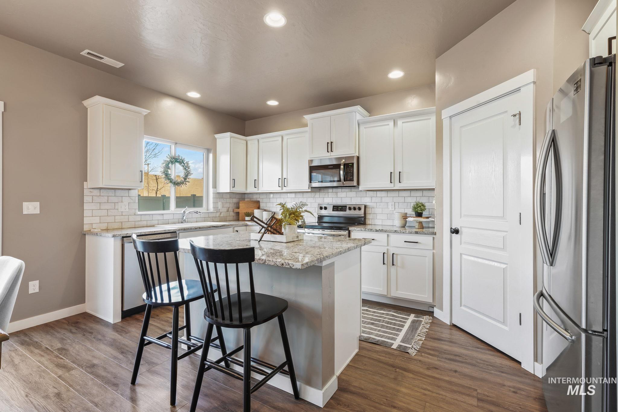 Kitchen featuring stainless steel appliances, a kitchen island, white cabinetry, a breakfast bar, and recessed lighting