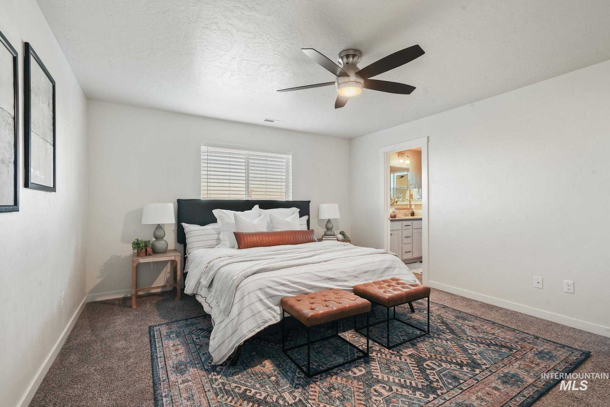 Bedroom with carpet, a textured ceiling, ceiling fan, and ensuite bathroom