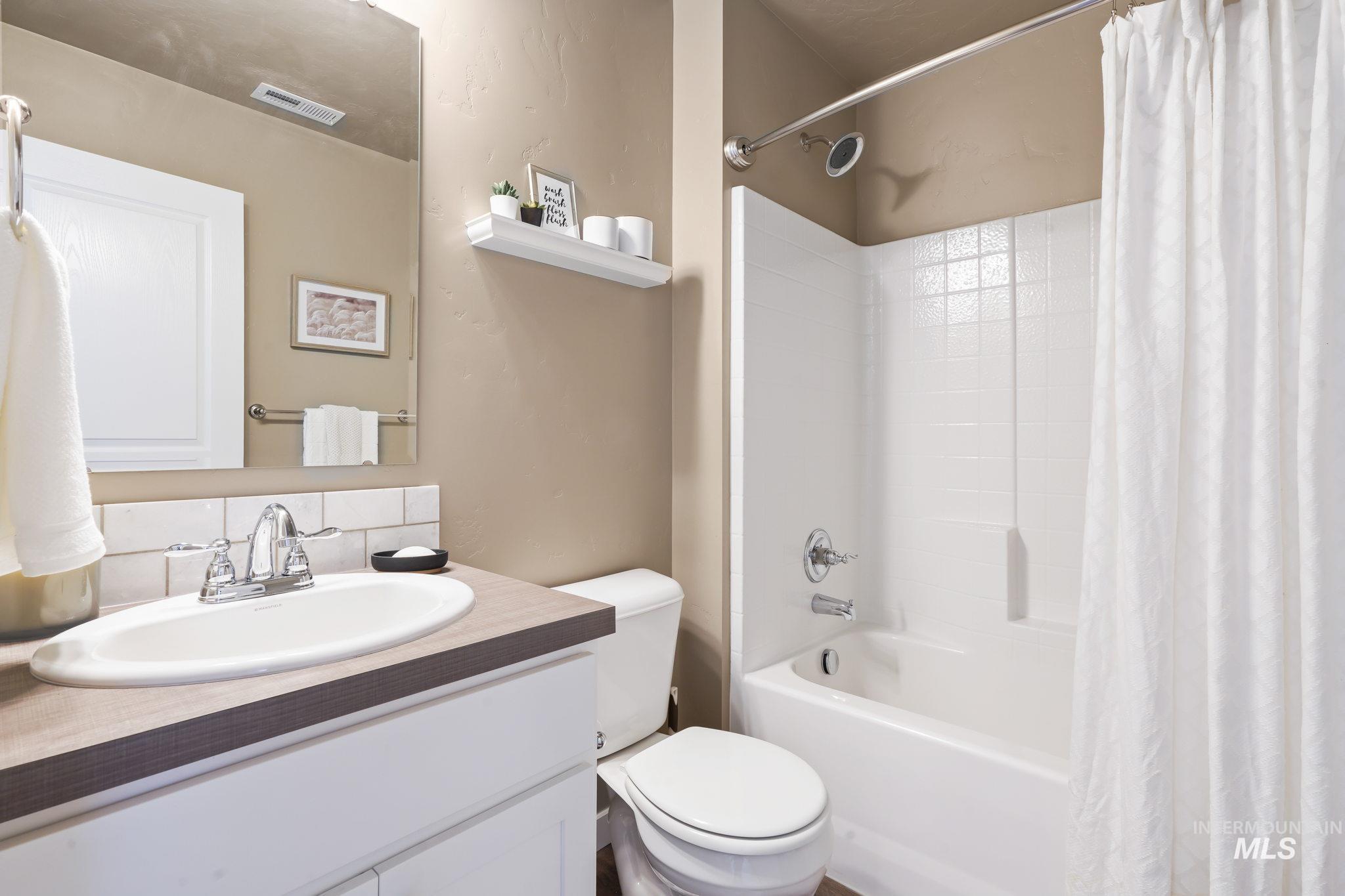 Full bathroom with shower / tub combo with curtain, vanity, and tasteful backsplash