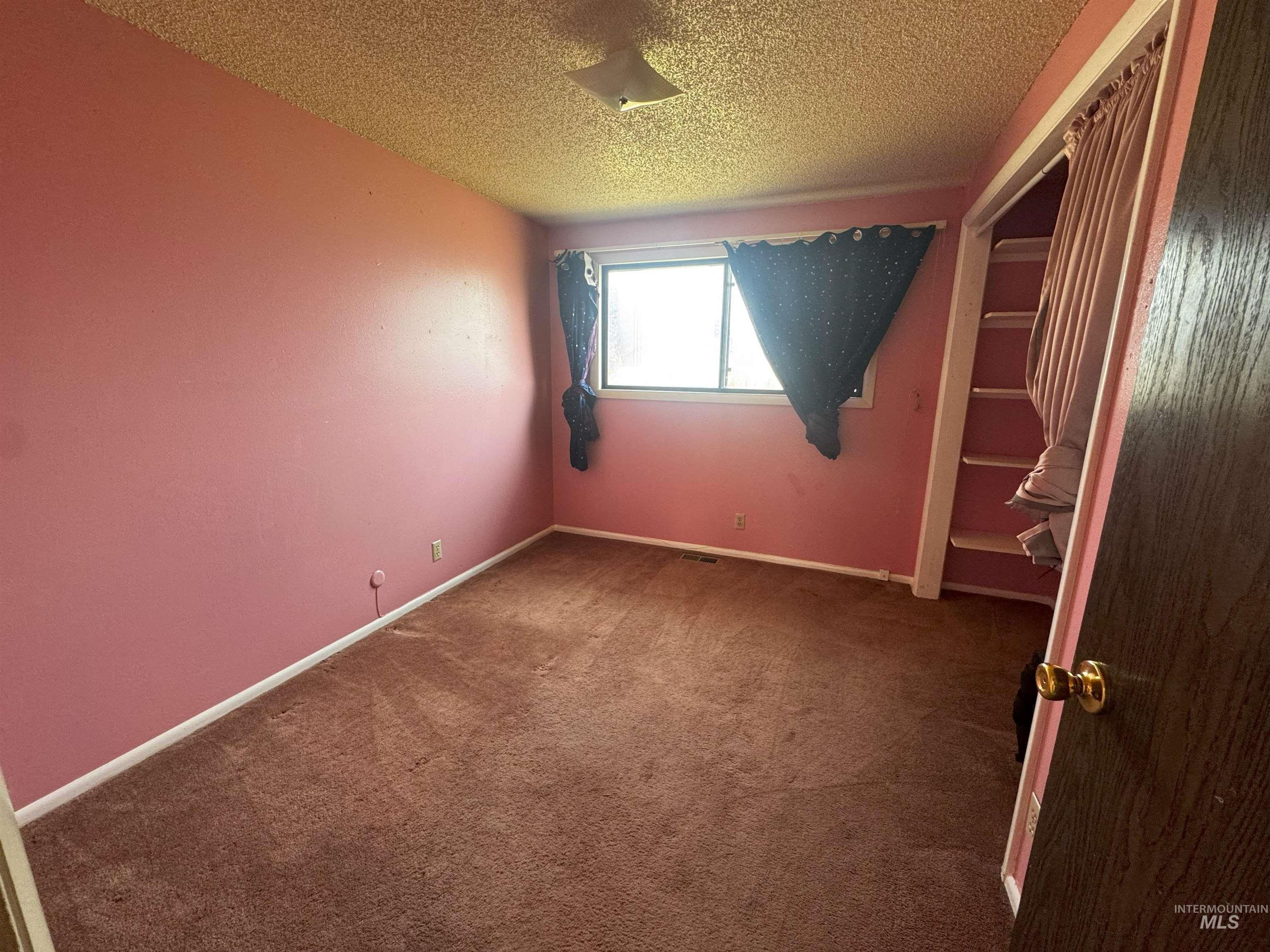 Unfurnished bedroom with carpet floors, a closet, and a textured ceiling